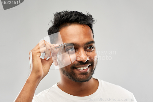 Image of indian man with tweezers tweezing eyebrow hair