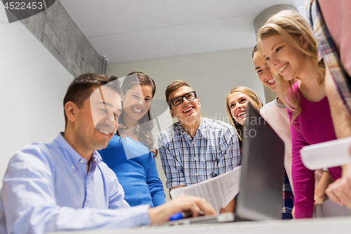 Image of students and teacher with papers and laptop