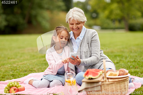 Image of grandmother and granddaughter with cell at park