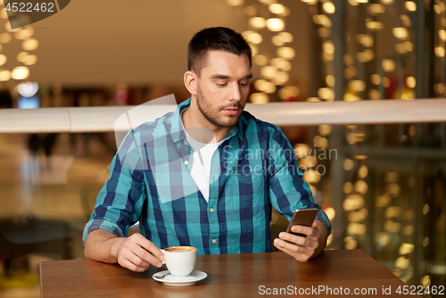Image of man with coffee and smartphone at restaurant
