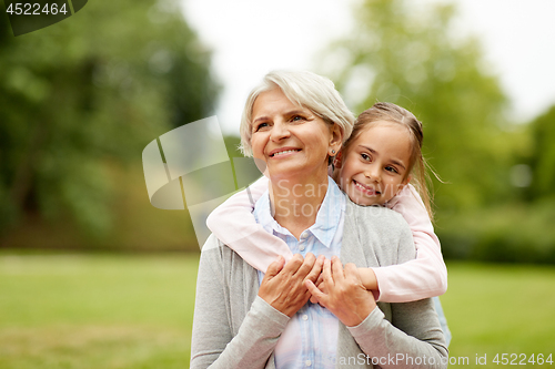 Image of granddaughter hugging grandmother at summer park