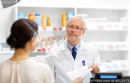 Image of senior apothecary with prescription at pharmacy