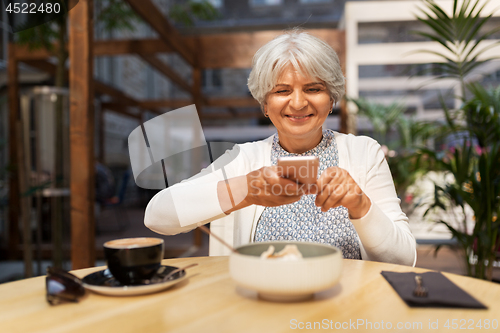 Image of senior woman photographing food at street cafe