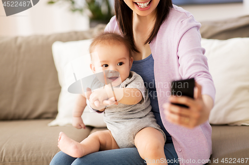 Image of mother with baby taking selfie at home