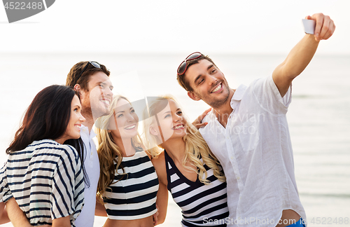 Image of happy friends taking selfie on summer beach