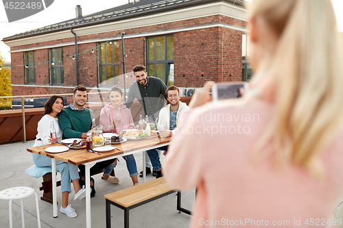 Image of happy friends photographing at rooftop party