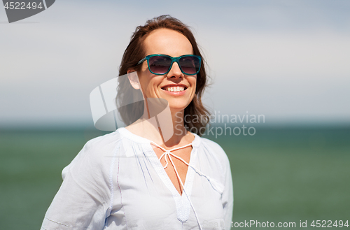 Image of happy smiling woman in sunglasses on summer beach