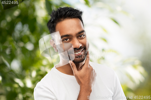 Image of smiling indian man touching his beard