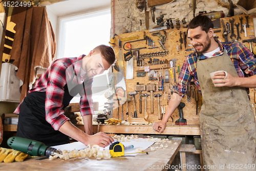 Image of carpenters with ruler and coffee at workshop