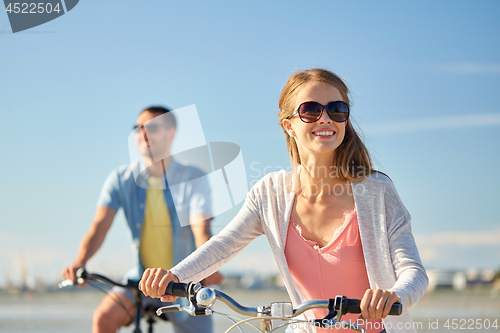 Image of happy young couple riding bicycles at seaside