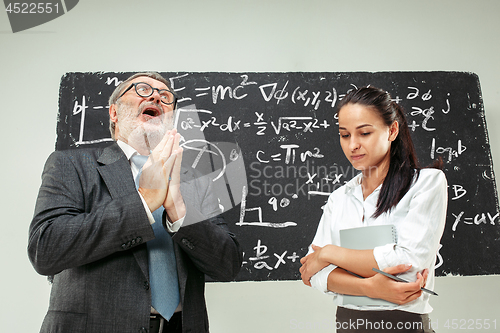 Image of Male professor and young woman against chalkboard in classroom