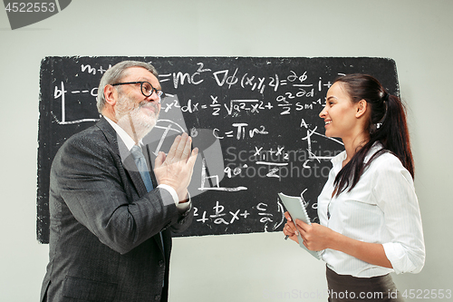 Image of Male professor and young woman against chalkboard in classroom