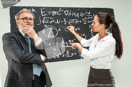 Image of Male professor and young woman against chalkboard in classroom