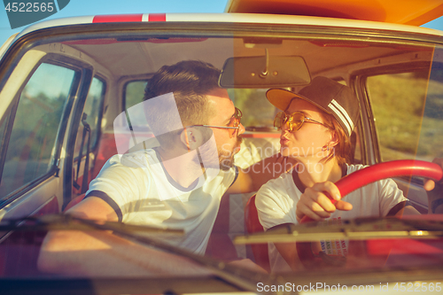 Image of Laughing romantic couple sitting in car while out on a road trip at summer day