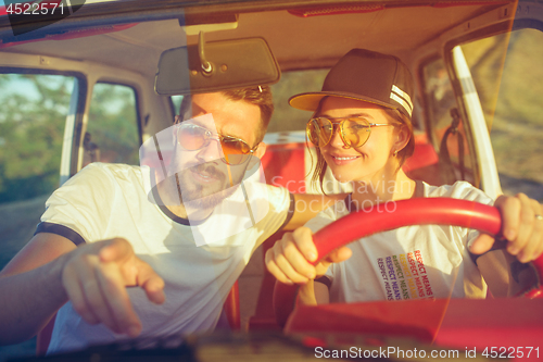 Image of Laughing romantic couple sitting in car while out on a road trip at summer day