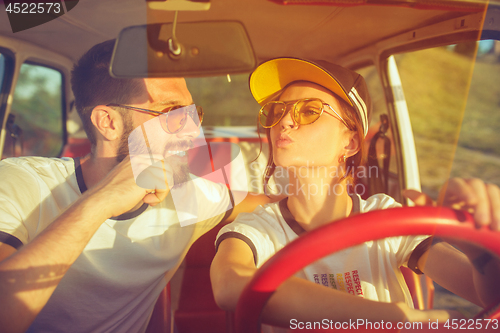 Image of Laughing romantic couple sitting in car while out on a road trip at summer day