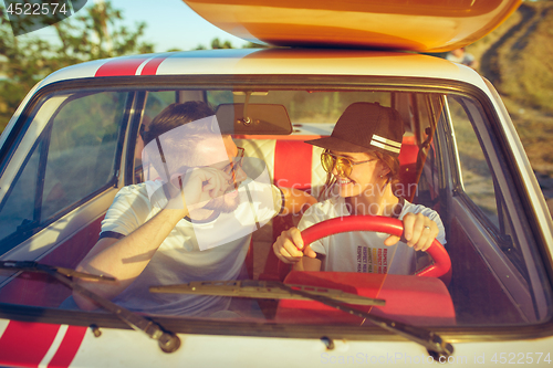 Image of Laughing romantic couple sitting in car while out on a road trip at summer day