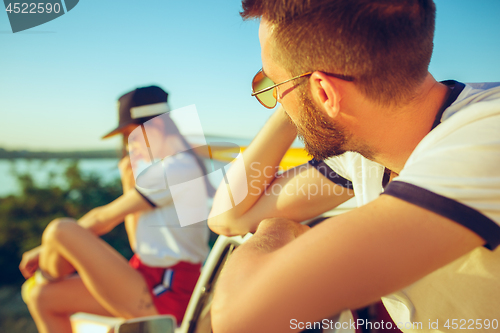 Image of Couple sitting and resting on the beach on a summer day near river