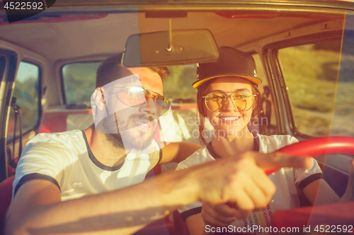 Image of Laughing romantic couple sitting in car while out on a road trip at summer day