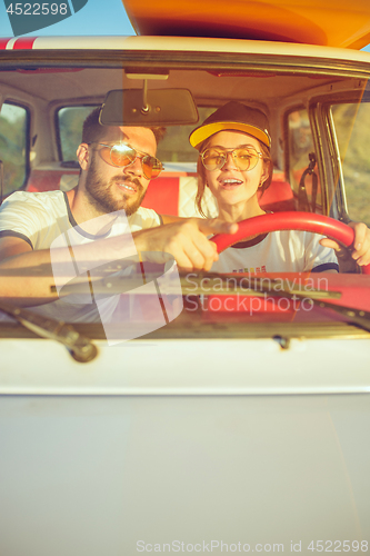 Image of Laughing romantic couple sitting in car while out on a road trip at summer day