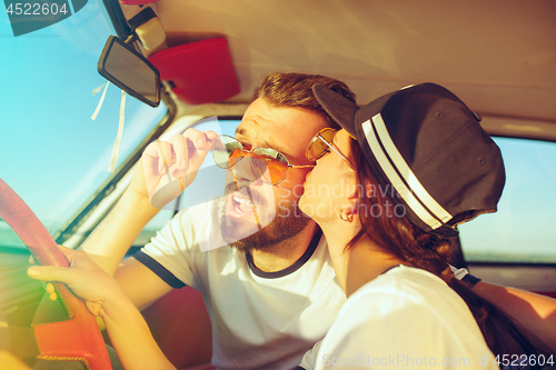 Image of Laughing romantic couple sitting in car while out on a road trip at summer day