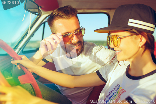 Image of Laughing romantic couple sitting in car while out on a road trip at summer day