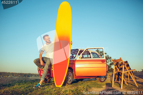 Image of The surfboard, car, man.