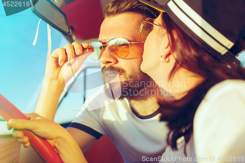Image of Laughing romantic couple sitting in car while out on a road trip at summer day