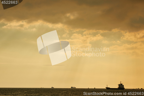 Image of Sunset over large body of water with rays of light coming through clouds