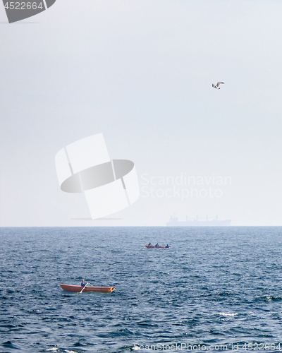 Image of View of fishing boats on a background of blue open sea and a tanker blurred on the horizon