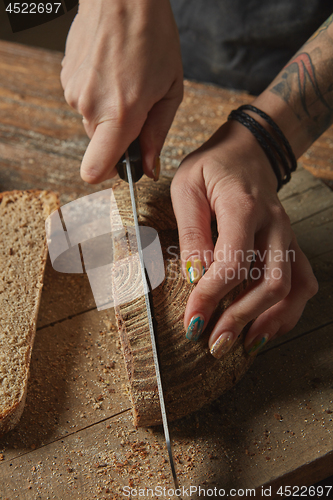 Image of Female hands cut freshly baked bread