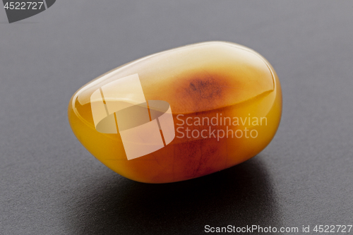 Image of Natural amber. A piece of yellow opaque natural amber on dark grey background.