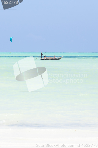 Image of fishing boat and a kite surfer on picture perfect white sandy beach with turquoise blue sea, Paje, Zanzibar, Tanzania.