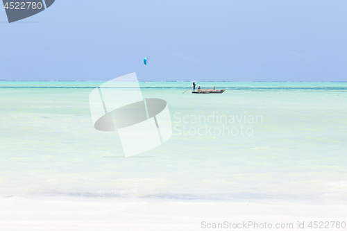 Image of fishing boat and a kite surfer on picture perfect white sandy beach with turquoise blue sea, Paje, Zanzibar, Tanzania.