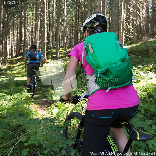 Image of Active sporty couple riding mountain bikes on forest trail .