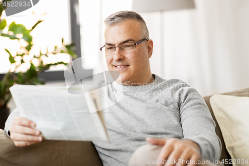 Image of man reading newspaper at home