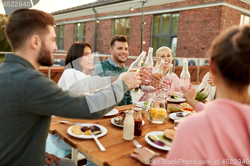 Image of happy friends toasting drinks at rooftop party