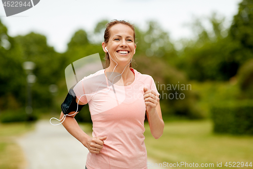 Image of woman with earphones add armband jogging at park