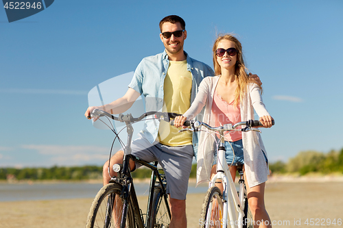 Image of happy young couple riding bicycles at seaside