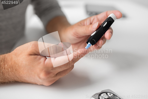 Image of senior man with glucometer checking blood sugar