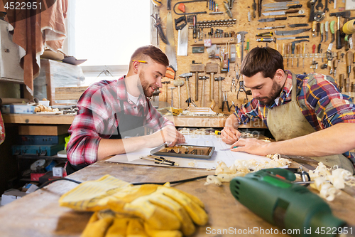 Image of carpenters with tablet and blueprint at workshop