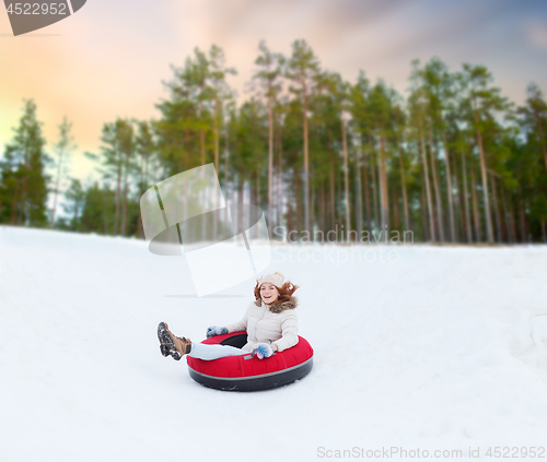 Image of happy teenage girl sliding down hill on snow tube