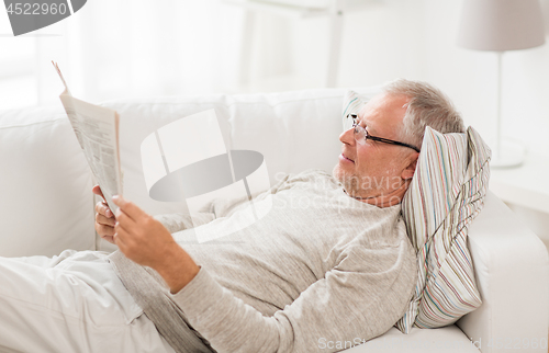 Image of senior man reading newspaper at home