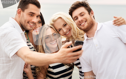 Image of happy friends taking selfie on summer beach