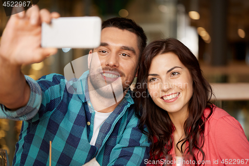Image of couple taking selfie by smartphone at restaurant