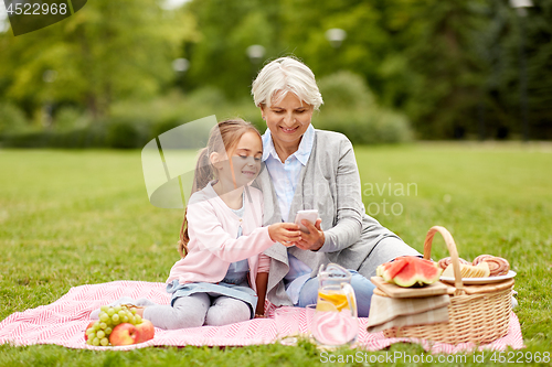 Image of grandmother and granddaughter with cell at park