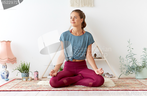 Image of woman meditating in lotus pose at yoga studio