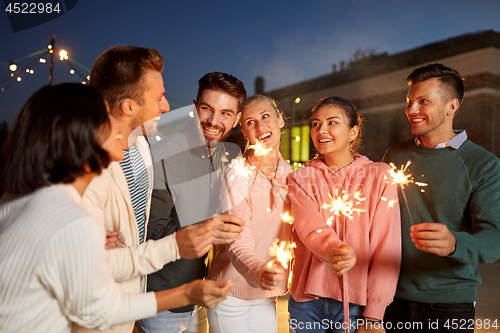 Image of happy friends with sparklers at rooftop party