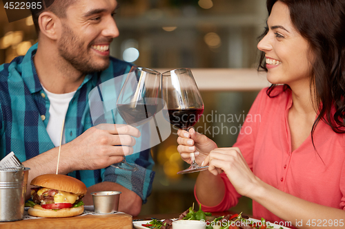 Image of couple eating and drinking red wine at restaurant