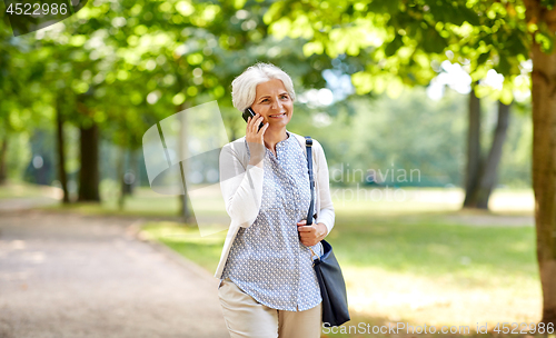 Image of senior woman calling on smartphone in summer park